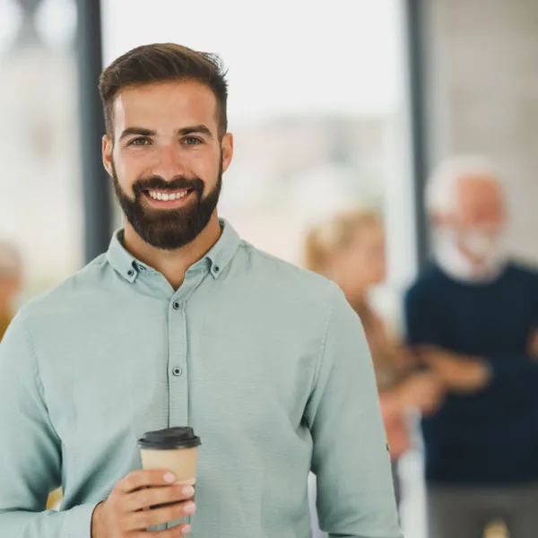 Portrait of host Jordan Hayes smiling, holding a coffee cup