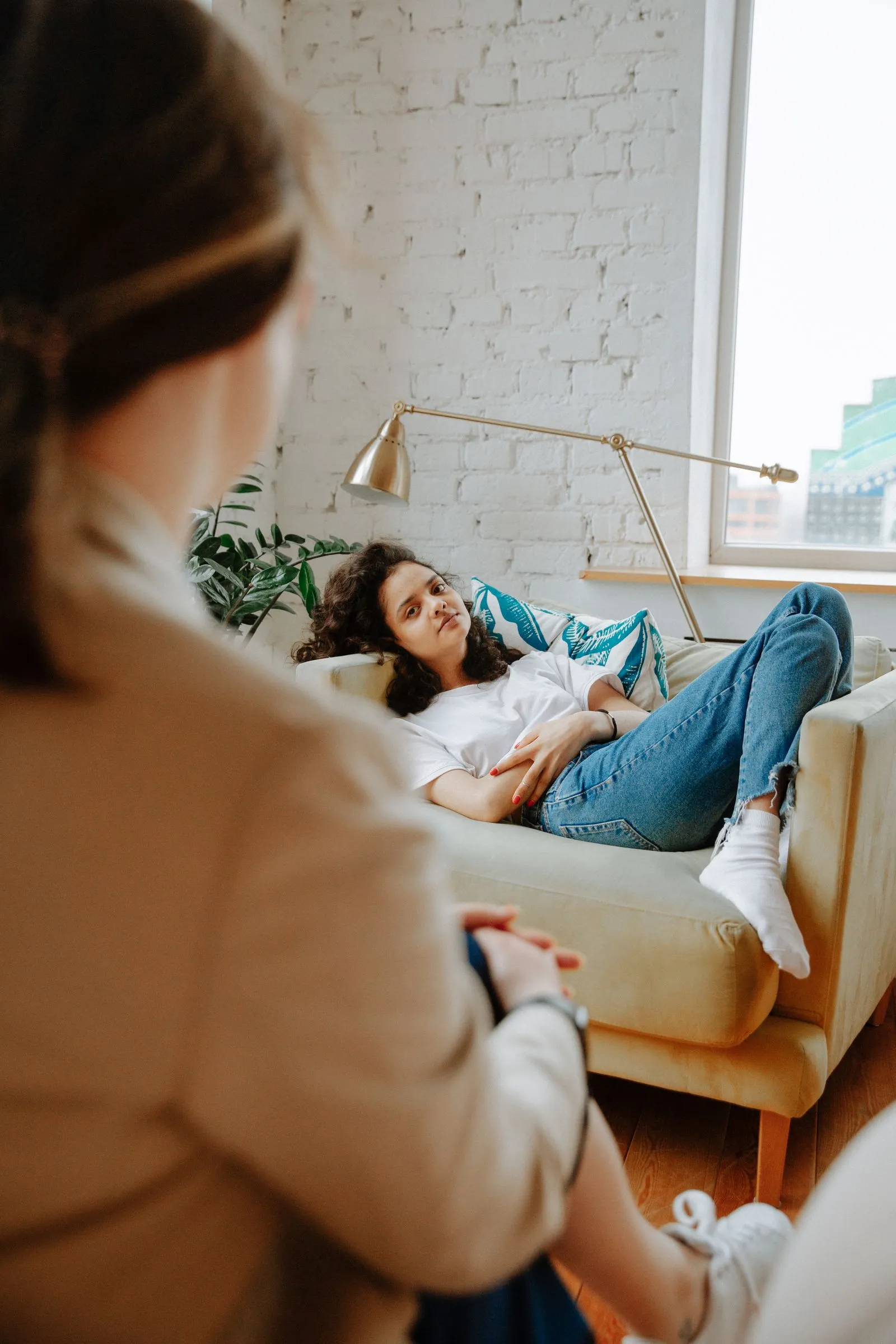 Therapist listening to a client relaxing on a sofa