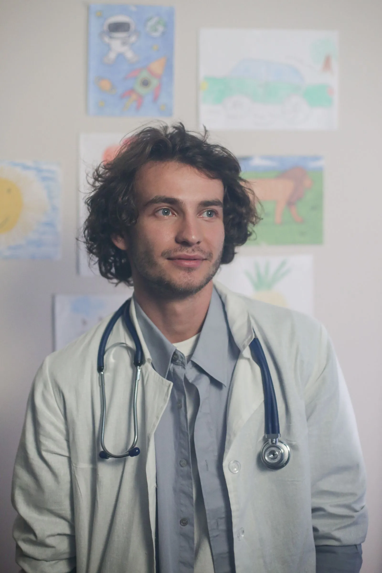 Smiling pediatric doctor with a stethoscope in front of children’s drawings
