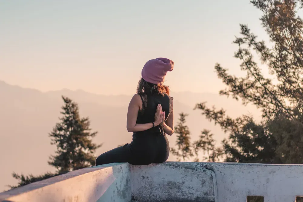 Woman practising yoga on a rooftop in reverse prayer pose