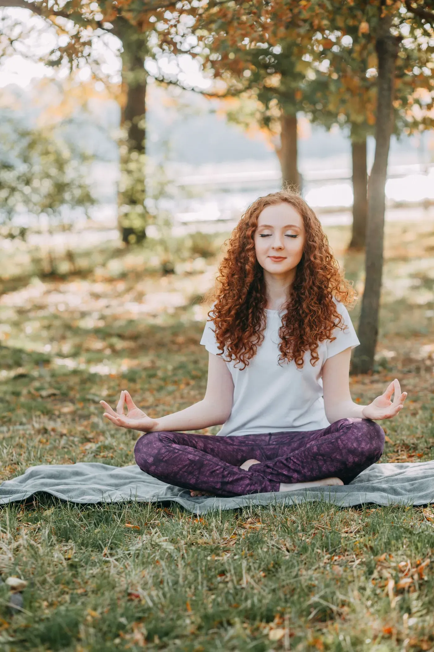 Woman meditating cross-legged on the grass in a park