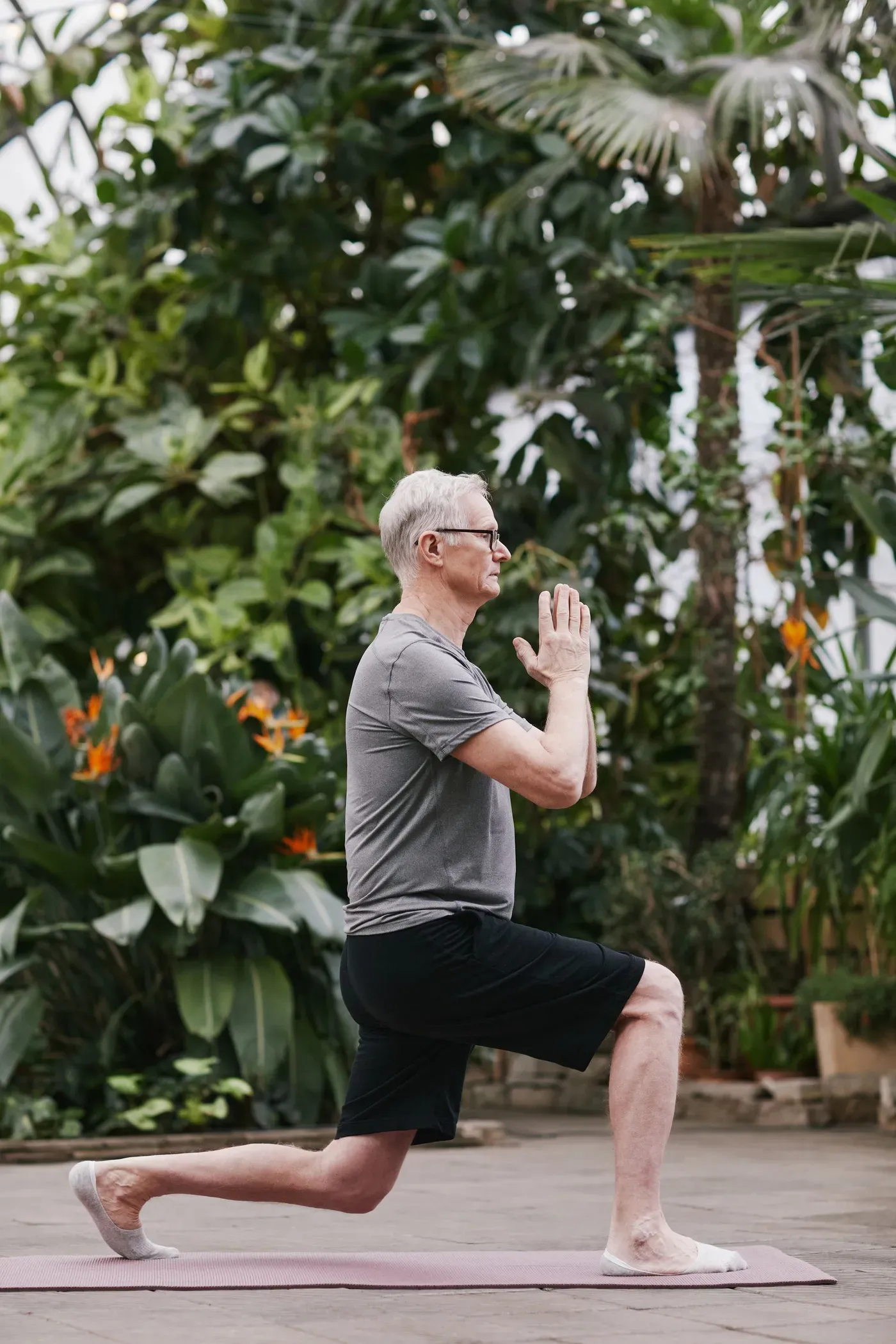 Older man practising slow movement outdoors among green plants