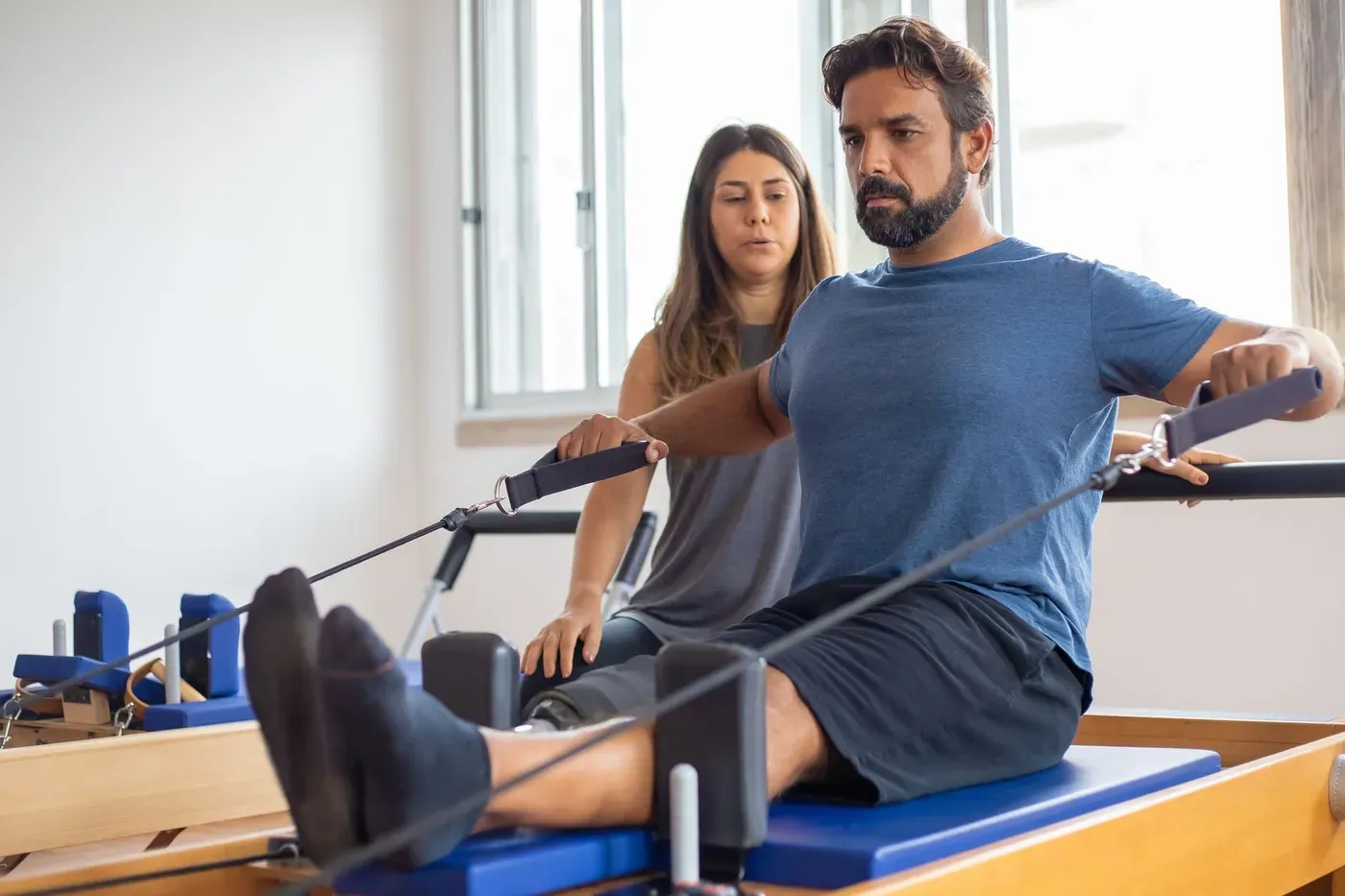 Instructor guiding a client on a pilates reformer
